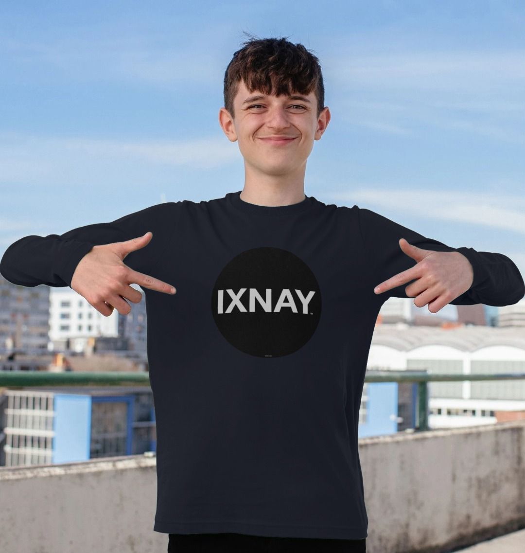 Boy smiling while standing on the upper deck of a parking garage and wearing a kids navy blue organic long-sleeved t-shirt with original black round IXNAY logo