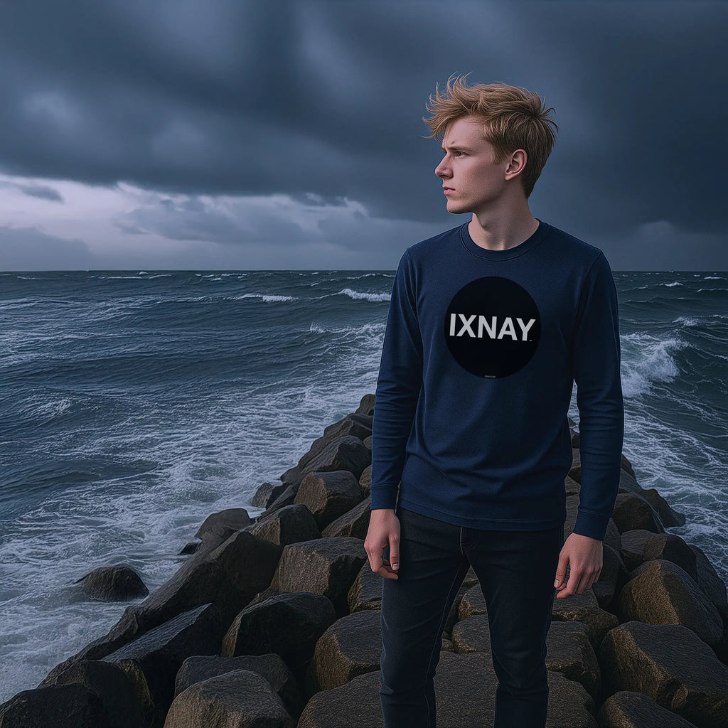 young man on rock jetty in storm tossed sea wearing navy blue IXNAY Original Logo 100% cotton long-sleeved t-shirt