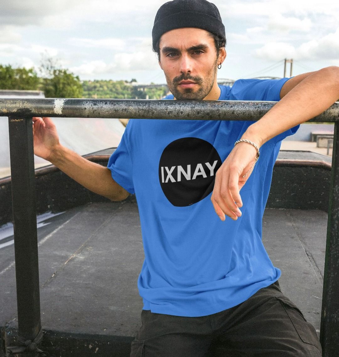 A man models a bright blue t-shirt with a black circular logo that reads 'IXNAY' on the front.