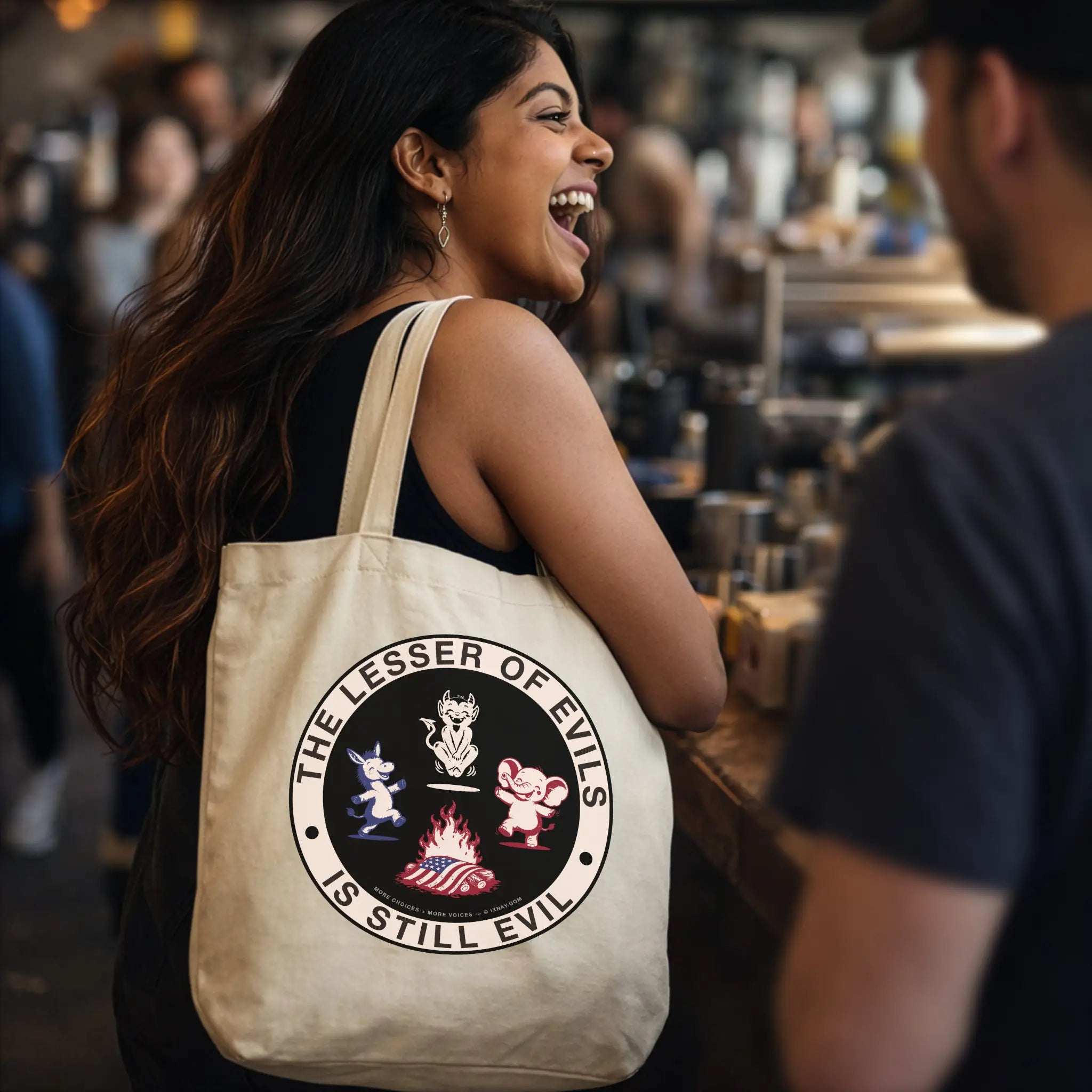 Laughing woman carrying oyster beige organic cotton tote bag with IXNAY's The Lesser of Evil is Still Evil graphic on front panel.