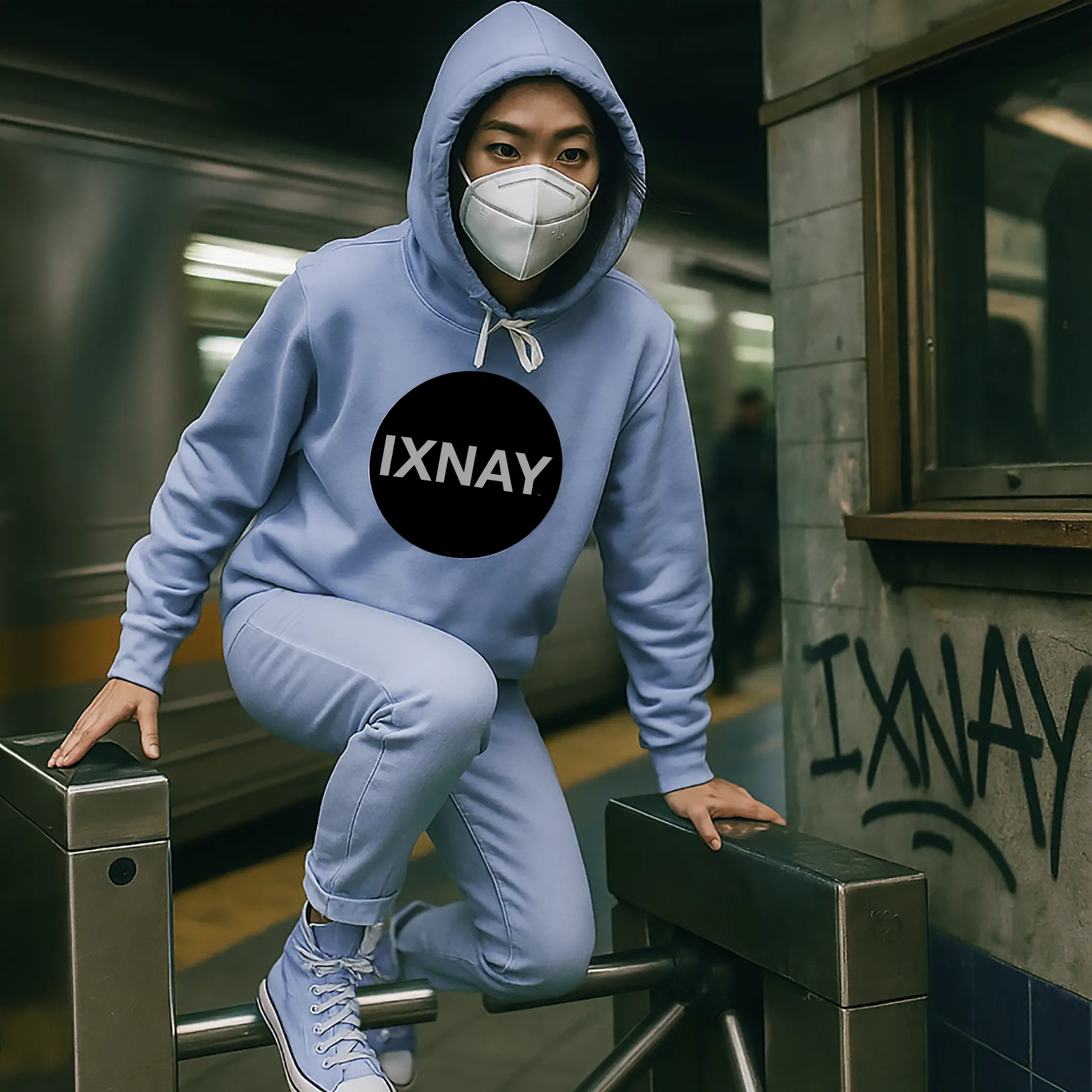 Rebellious woman jumping subway turnstile wearing women's lightweight baby blue hoodie with IXNAY original logo in 100% cotton.