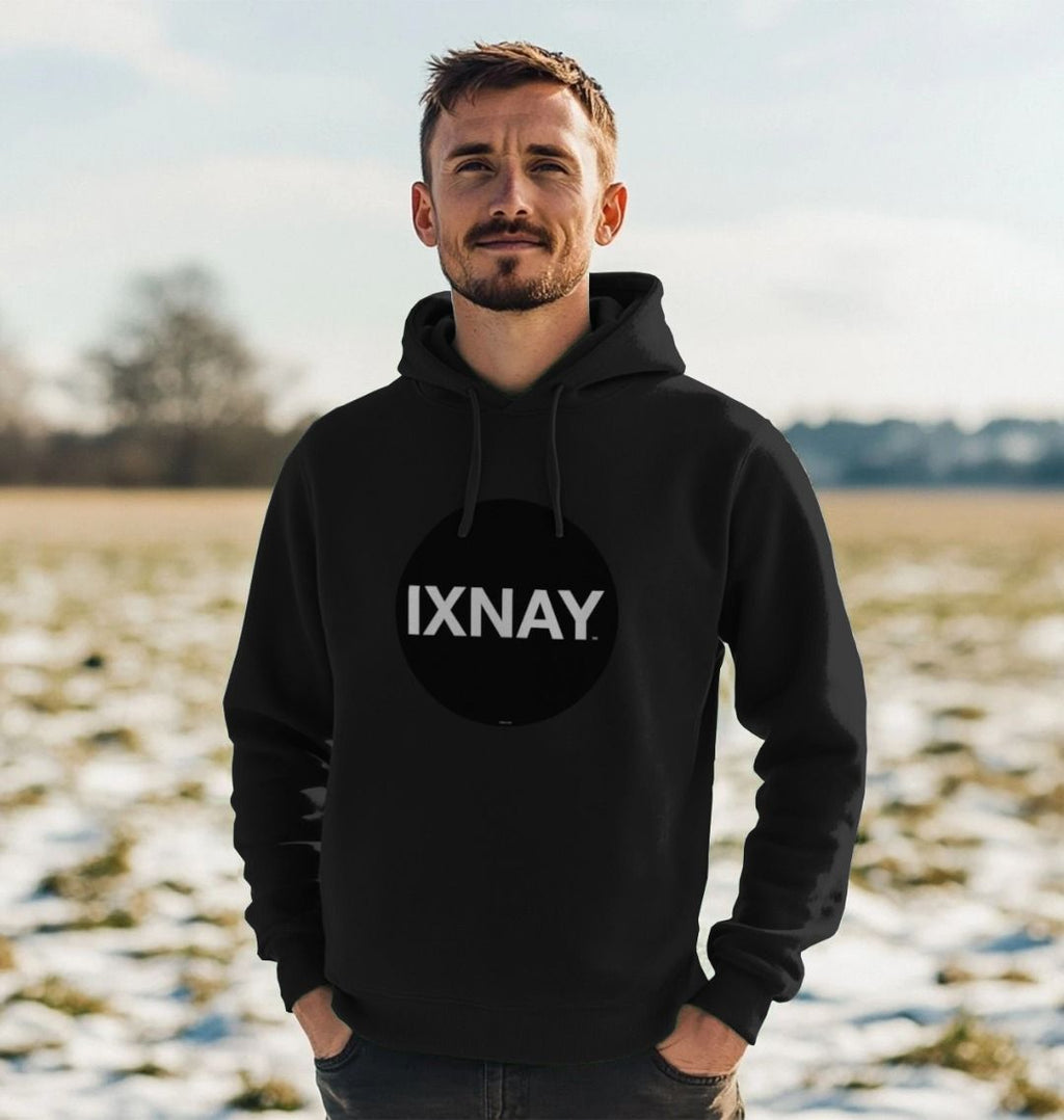 Man in partially snowy field wearing mens black organic cotton pullover hoodie with original black round IXNAY logo