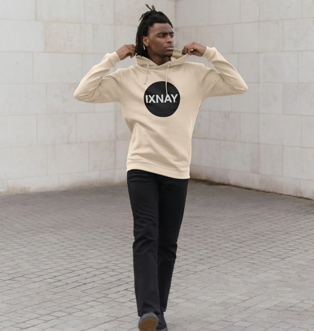 Black man in front of white marble wall wearing mens oat light beige organic cotton pullover hoodie with original black round IXNAY logo