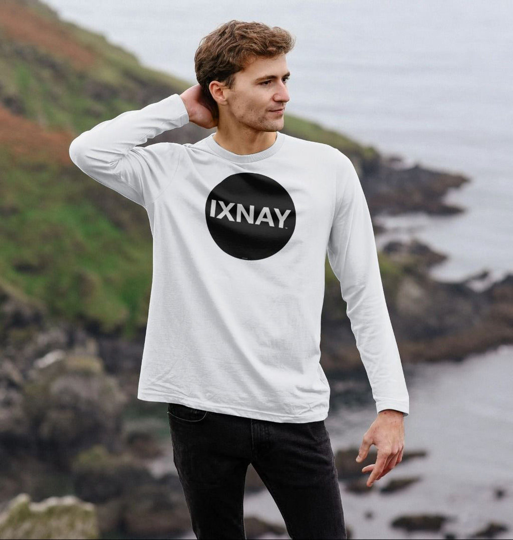 Man viewing ocean from top of cliff wearing White Printed Men's Long-sleeved T-Shirt with Original Black Round IXNAY Logo from the artist and musician IXNAY