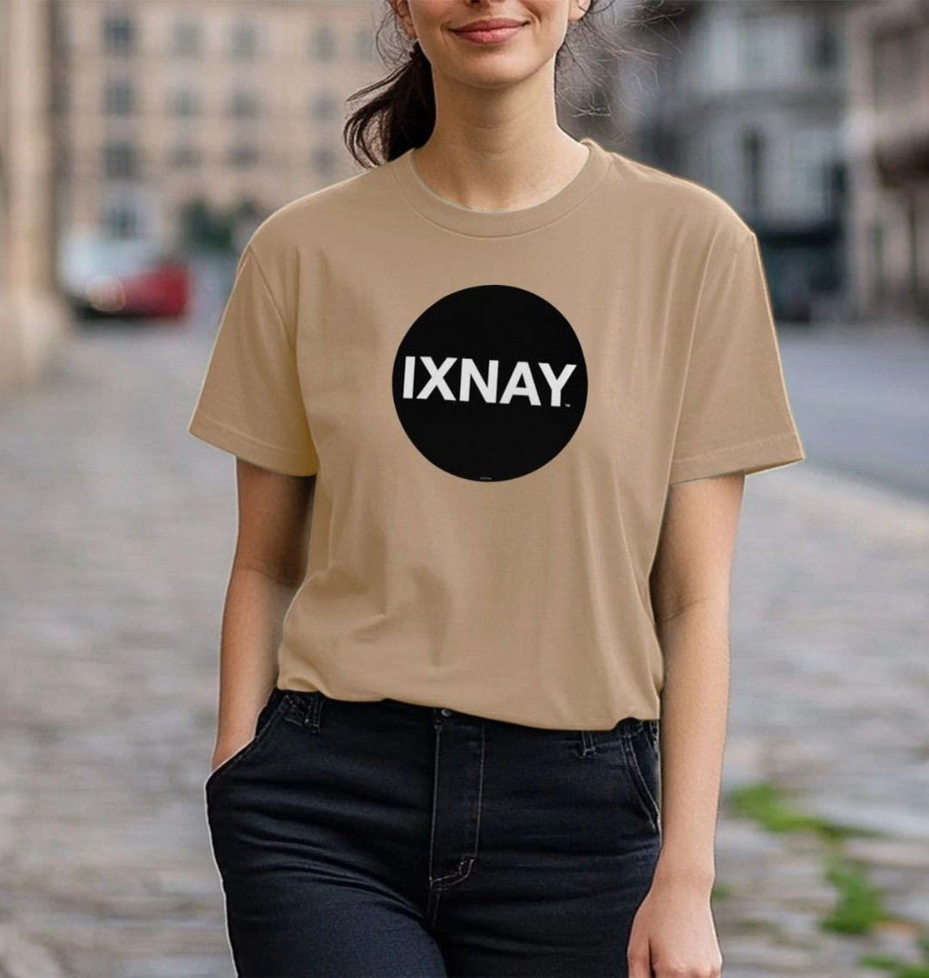 Woman with one hand in her jeans pocket smiling while walking down a cobblestone street wearing a sand light brown Printed Women's T-Shirt with Original Black Circular IXNAY Logo